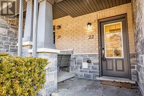 Guelph (Pineridge/Westminster Woods) townhouse for rent - A house numbered 22 with a grey door and a stone wall.