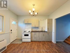 Fort Erie (Central) apartment for rent - A kitchen with a white stove top oven and wooden cabinets.