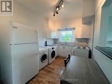 Fort Erie (Central) apartment for rent - A white refrigerator is in a kitchen with wooden floors and white cabinets.