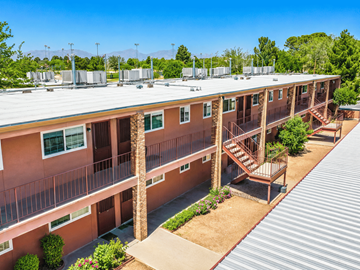 El Paso apartment for rent - A view of a courtyard with a metal roof and a building with red walls and balconies.