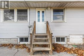 Thorold (Thorold Downtown) multi-family for rent - A house with a white door and a wooden staircase leading to it.