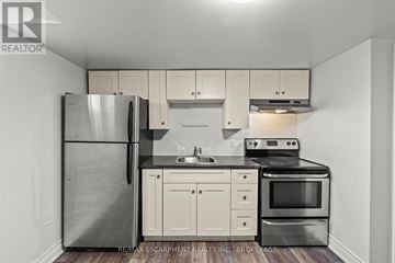 Thorold (Thorold Downtown) multi-family for rent - A kitchen with white cabinets and a stainless steel refrigerator.