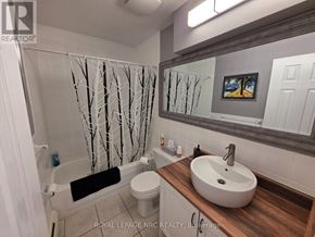 St. Catharines (Oakdale) condo for rent - A bathroom with a white toilet, a white sink, and a white shower curtain.
