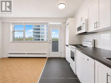 Toronto (Annex) condo for rent - A kitchen with white cabinets and a black countertop.