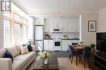 Toronto (Casa Loma) condo for rent - A well-lit, modern kitchen with white appliances and a dining area with a table set for two.
