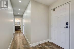 London South (South D) condo for rent - A hallway with a white door and a sign that says "THE REALTY FIRM INC., Brokerage".