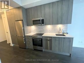 Toronto (Church-Yonge Corridor) condo for rent - A modern kitchen with stainless steel appliances and wooden cabinets.