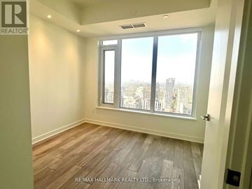 Toronto (Annex) condo for rent - A room with a view of the city through large windows.