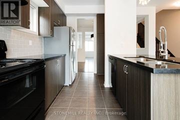 Mississauga (Churchill Meadows) townhouse for rent - A modern kitchen with dark wood cabinets and a black stove top oven.
