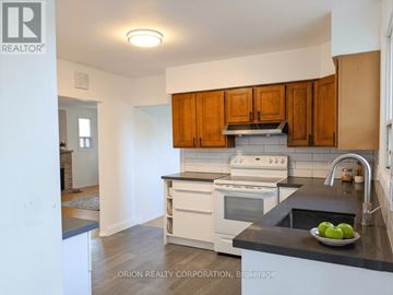 Hamilton (Eastmount) multi-family for rent - A kitchen with white appliances and wooden cabinets.