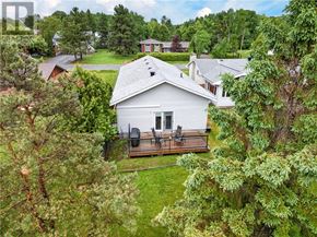 Lively apartment for rent - A white house with a grey roof is surrounded by trees.