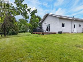 Lively apartment for rent - A house with a white exterior and a black grill is surrounded by a green lawn.