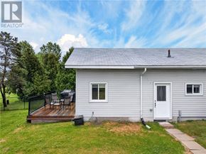 Lively apartment for rent - A house with a grey roof and a white door is surrounded by green grass.