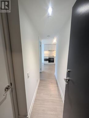 Toronto (Bay Street Corridor) condo for rent - A hallway with a door on the left and a kitchen in the distance.