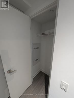 Toronto (Bay Street Corridor) condo for rent - A white door with a handle is in the foreground of a room with a light switch on the wall.