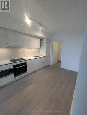 Toronto (Bay Street Corridor) condo for rent - A modern kitchen with white cabinets and a wooden floor.
