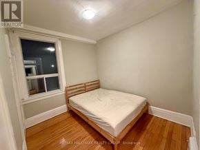 Ottawa triplex for rent - A bedroom with a bed, wooden floors, and a window.