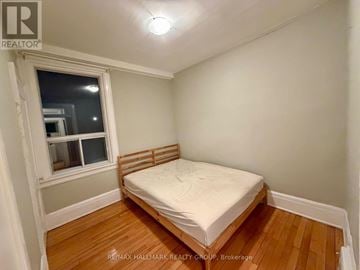 Ottawa triplex for rent - A bedroom with a bed, wooden floors, and a window.
