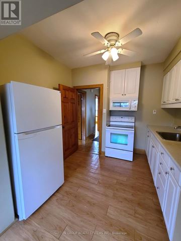 Toronto (Runnymede-Bloor West Village) duplex for rent - A kitchen with a white refrigerator and wooden cabinets.