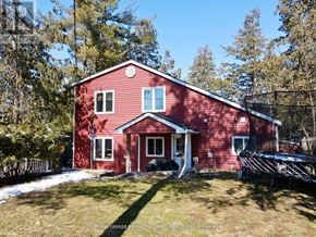 Ramara apartment for rent - A red house with a white door and windows is surrounded by trees.