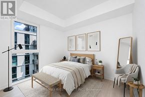 Toronto (Clanton Park) condo for rent - A bedroom with a large bed, a chair, and a mirror.