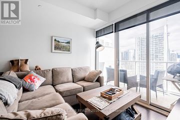 Toronto (Waterfront Communities) condo for rent - A living room with a grey couch and a coffee table in front of a large window.