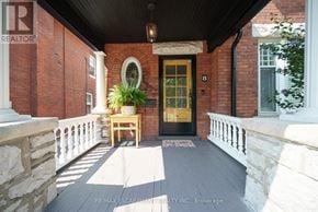 Brantford apartment for rent - A front porch with a wooden bench and a potted plant.
