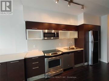 Toronto (Bay Street Corridor) condo for rent - A kitchen with dark brown cabinets and stainless steel appliances.
