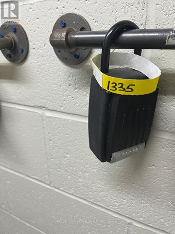 Toronto (Bay Street Corridor) condo for rent - A black padlock with the number 1335 on a yellow tag is attached to a metal rod.