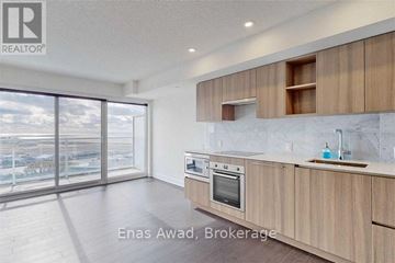 Toronto (Waterfront Communities) condo for rent - A modern kitchen with wooden cabinets and a marble countertop.