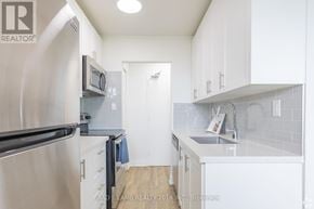Hamilton (Rosedale) condo for rent - A kitchen with white cabinets and a black refrigerator.