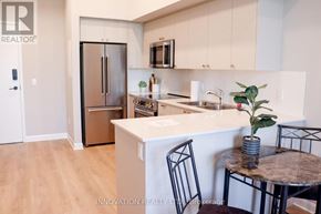 North Grenville apartment for rent - A modern kitchen with a refrigerator, sink, and a dining table with chairs.