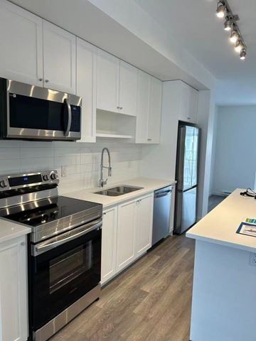 Surrey townhouse for rent - A kitchen with white cabinets and a black stove top oven.