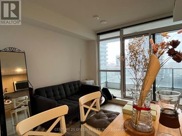 Toronto (Waterfront Communities) condo for rent - A living room with a black couch and a wooden coffee table.