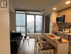 Toronto (Waterfront Communities) condo for rent - A well-lit kitchen and living room with a view of the city.