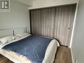 Toronto (Waterfront Communities) condo for rent - A bedroom with a bed, pillows, and a wooden wardrobe.