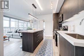 Toronto (Waterfront Communities) condo for rent - A modern kitchen with dark wood cabinets and a white countertop.