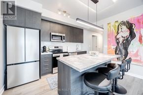 Toronto (Waterfront Communities) condo for rent - A modern kitchen with a large island and a refrigerator.