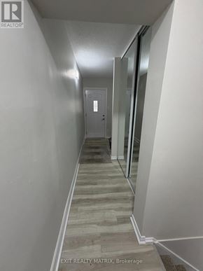 Ottawa townhouse for rent - A hallway with wood flooring and white walls leading to a door.