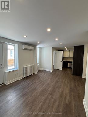 Toronto (Forest Hill South) house for rent - A spacious room with wood flooring and a window with a radiator beneath it.