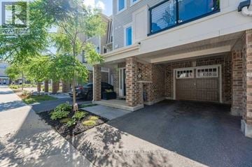 Kitchener townhouse for rent - A residential building with a garage and a tree in front.