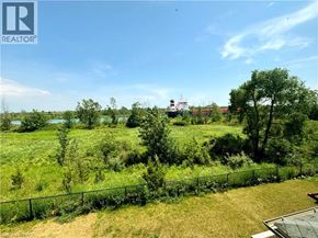 Welland apartment for rent - A lush green field with a fence and a building in the distance.