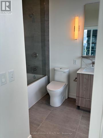 Toronto (Mount Pleasant West) condo for rent - A white toilet sits in a bathroom with a glass shower door.