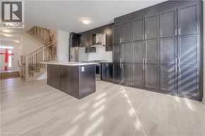 Oakville townhouse for rent - A modern kitchen with a wooden floor and a staircase in the background.