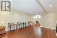Brampton (Snelgrove) apartment for rent - A realtor logo is on a wall in a room with wood floors and chairs.
