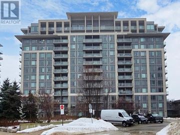 Markham (Commerce Valley) condo for rent - A large, modern apartment building with a parking lot in front.