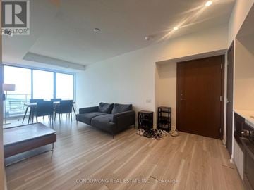 Toronto (Waterfront Communities) condo for rent - A living room with a black couch and a wooden floor.