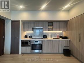 Toronto (Waterfront Communities) condo for rent - A modern kitchen with wooden cabinets and stainless steel appliances.