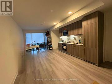 Toronto (Annex) condo for rent - A spacious kitchen with wooden cabinets and a dining table with chairs.