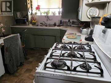 Oshawa (Central) apartment for rent - A kitchen with a gas stove and a sign that says "REALTOR".